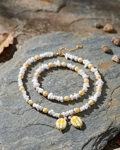Charming yellow flower beaded necklace made with ceramic and crystal displayed on a weathered slate stone surface.