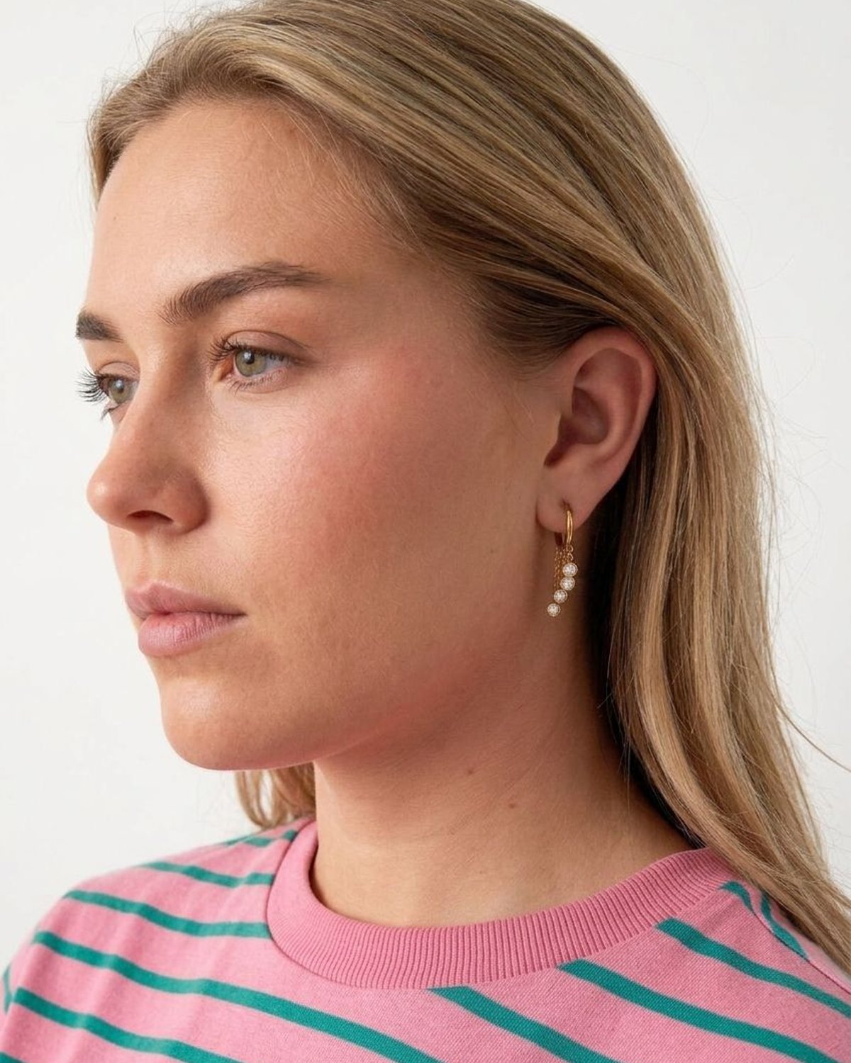 Chic circle drop earrings with shimmering zircon stones resting on a textured linen surface.