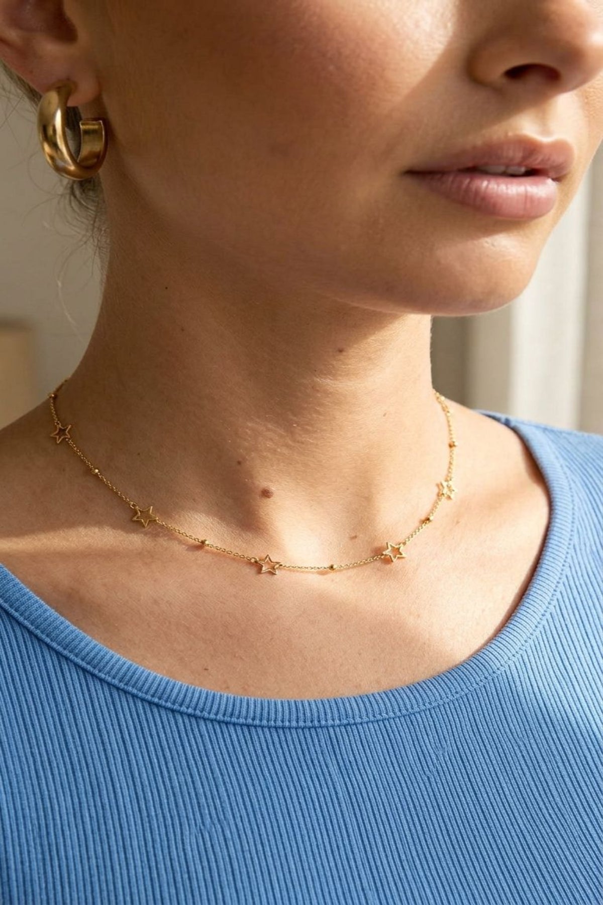 Detailed close-up of the Celestial Bestie Gold necklace highlighting star motifs and fine chain against soft fabric.