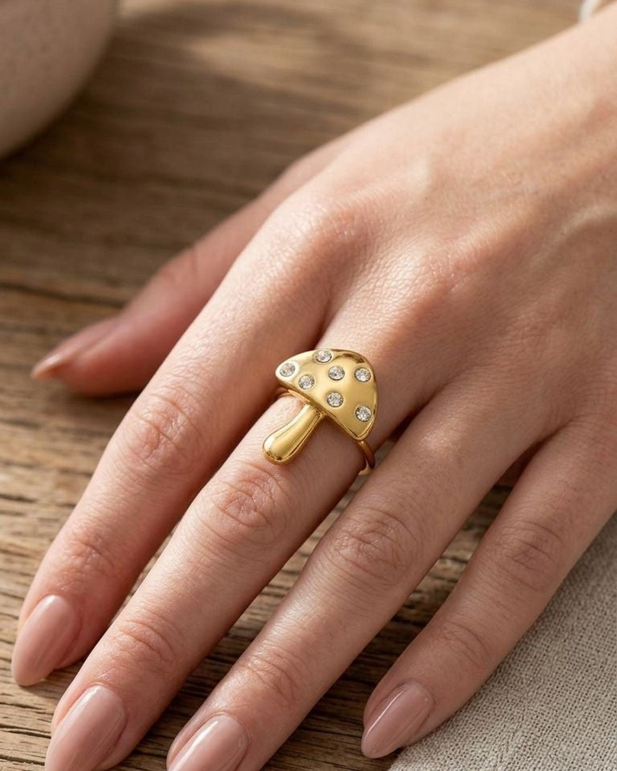 Close-up of Golden Mushroom Statement Ring on a slender finger, highlighting rhinestone accents and smooth gold-toned design in natural daylight.