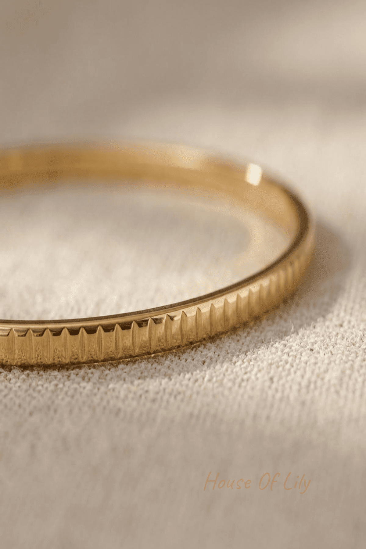 Detailed macro shot of a gold stainless steel textured bangle highlighting groove details and polished surface with warm lighting.