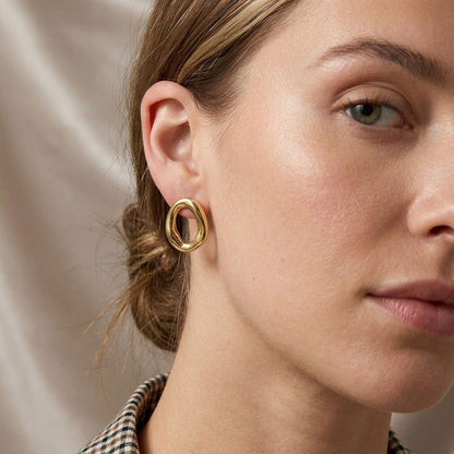 Close-up of Organic Wave Studs earrings showcasing their sculptural wave form and shiny stainless steel texture.