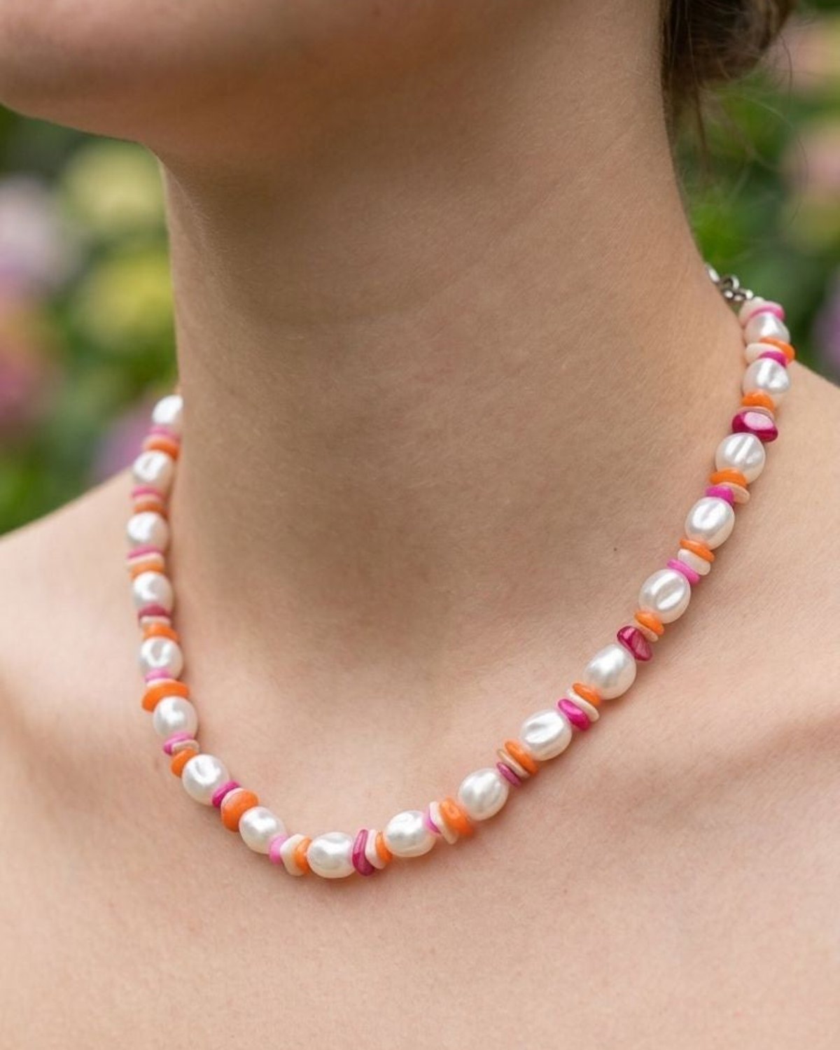 Close-up of colourful pearl beaded necklace on model's collarbone showcasing pastel and vibrant beads in a playful design.