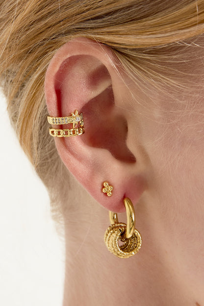 Model wearing gold star and chain link ear cuff on upper ear, paired with other gold earrings