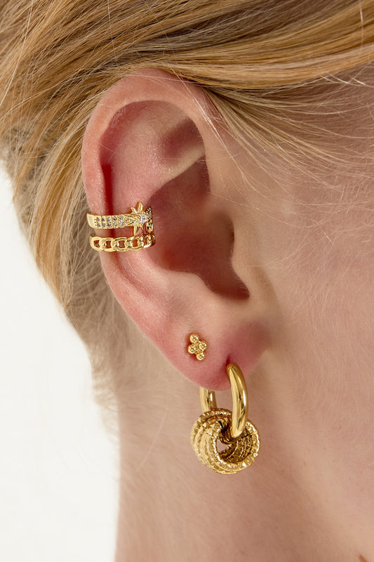 Model wearing gold star and chain link ear cuff on upper ear, paired with other gold earrings