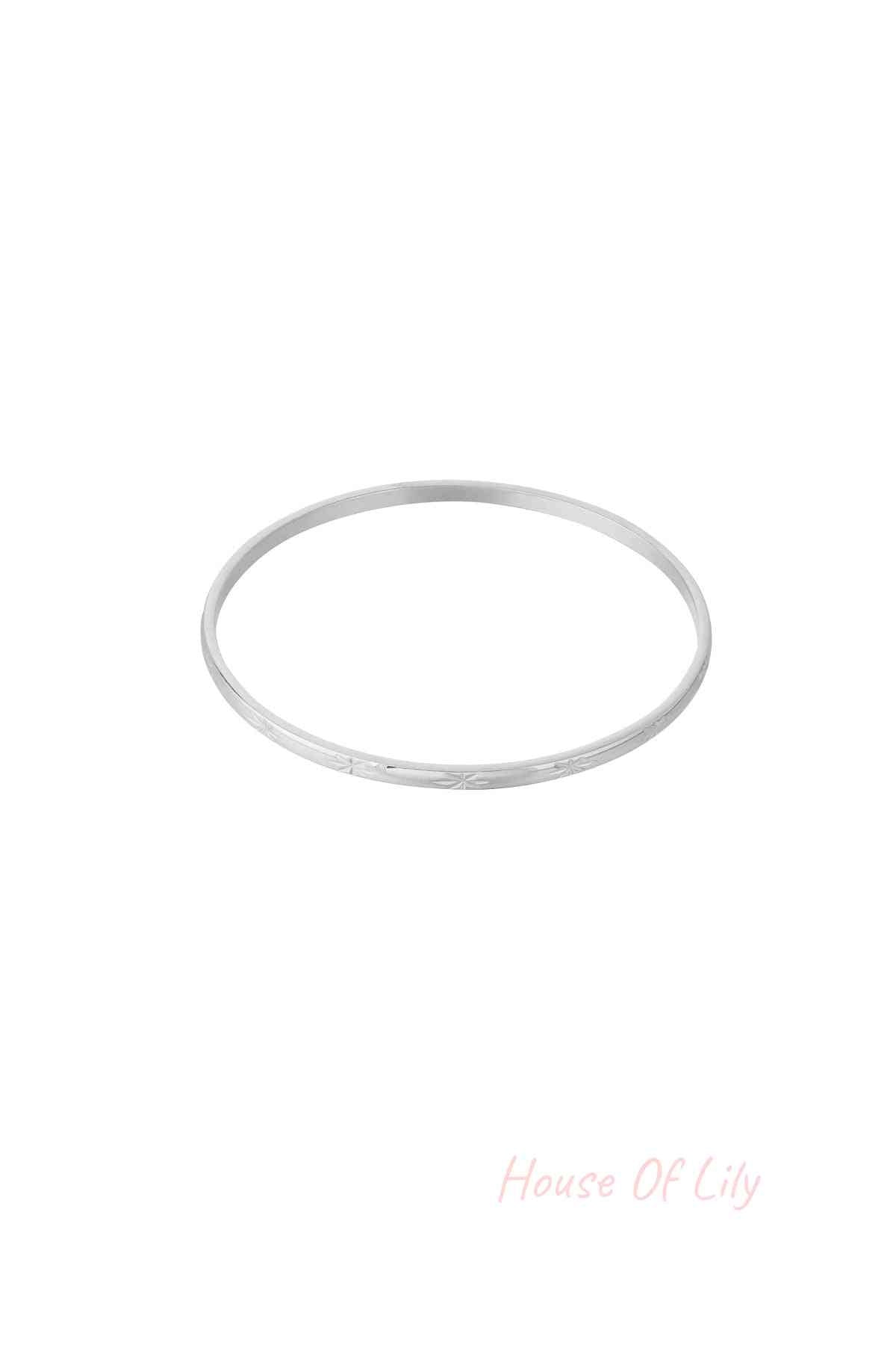 Silver slender minimalist bangle bracelet with subtle starburst engraving on a white background