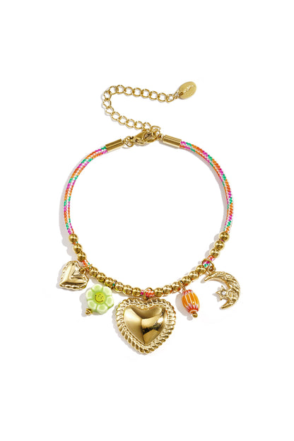 Gold charm bracelet with multicolor rope and various pendants including a large heart, green flower, orange bead, small heart, and crescent moon