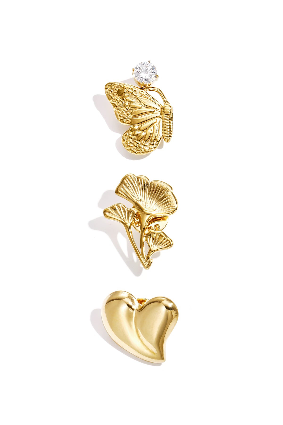 Three gold-tone brooches displayed on white background: butterfly with rhinestone, floral sprig, and heart shape.