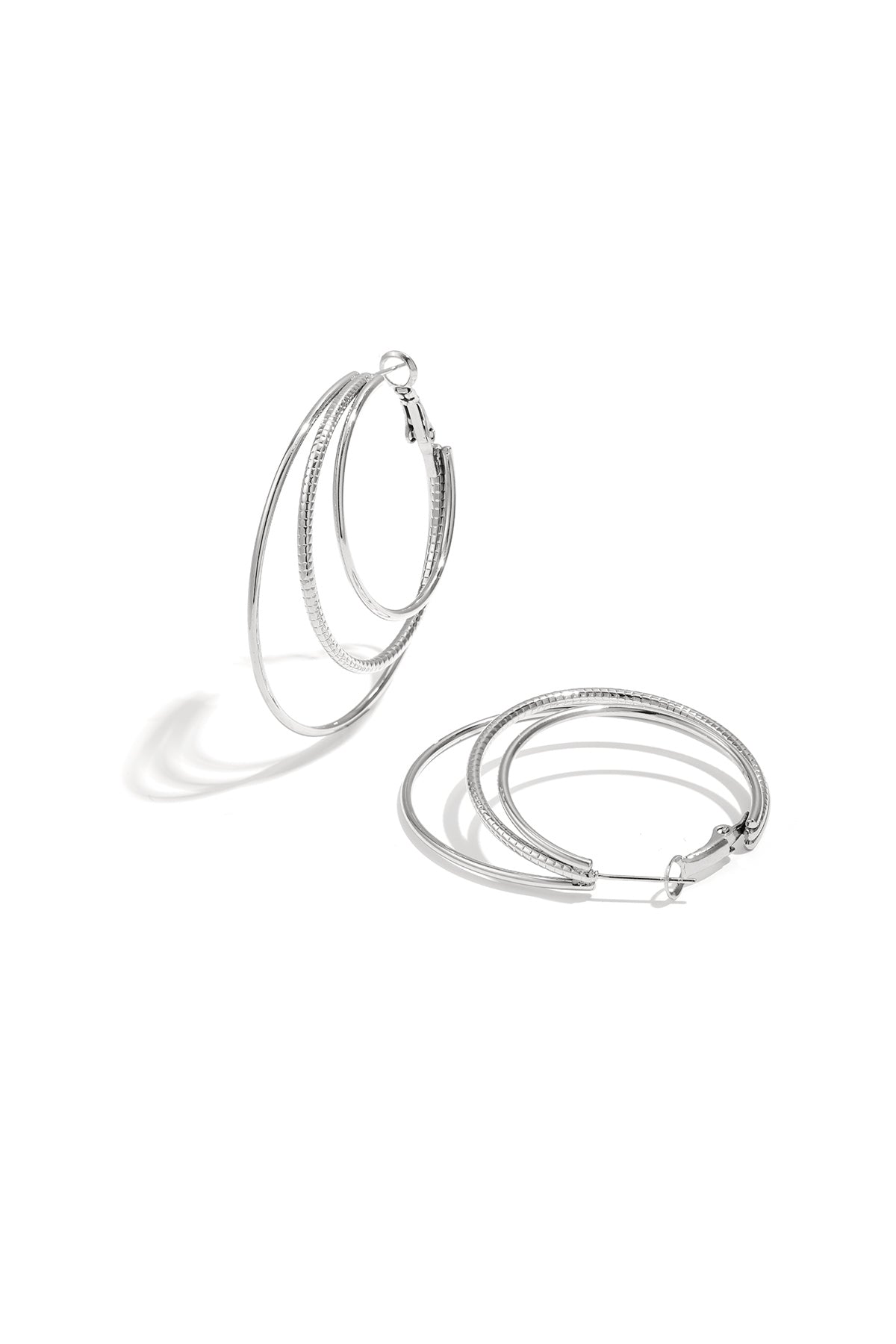 Close-up of silver triple layered hoop earrings on white background with three nested hoops showing smooth and textured finishes