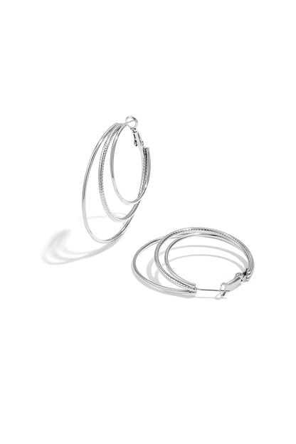 Close-up of silver triple layered hoop earrings on white background with three nested hoops showing smooth and textured finishes