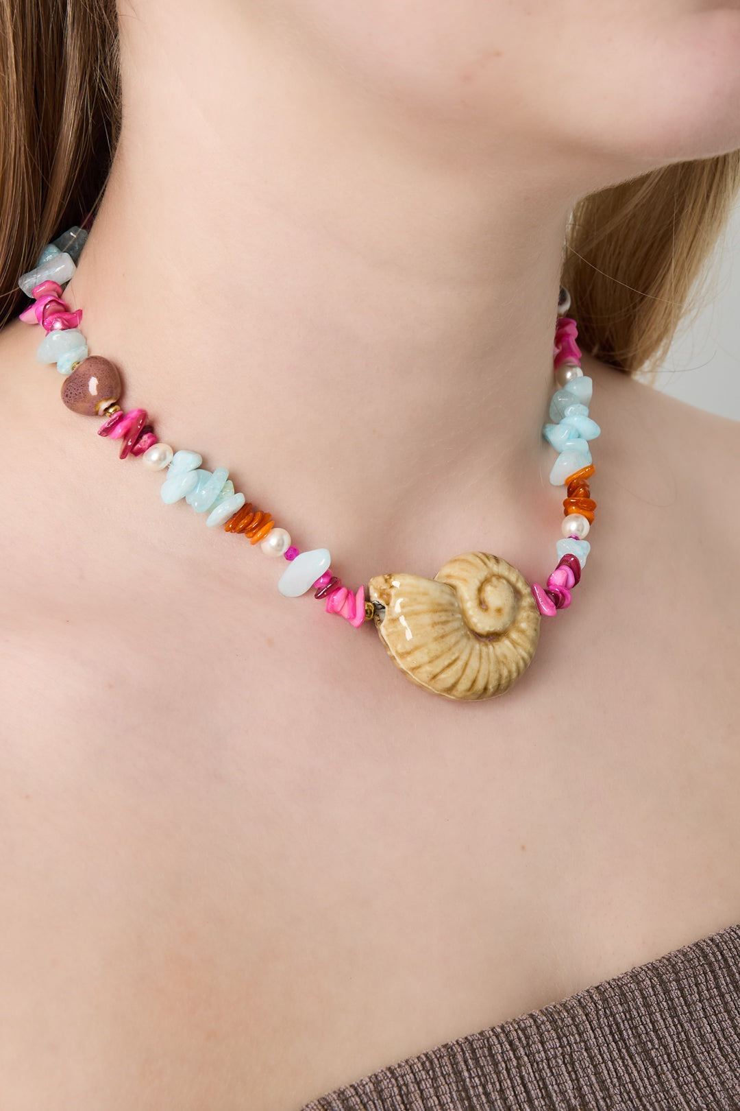 Model wearing a colorful shell beaded necklace close up showing stones and beads detail