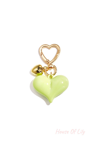 Single green heart acrylic bag charm with gold heart clasp and mini gold heart pendant on white background