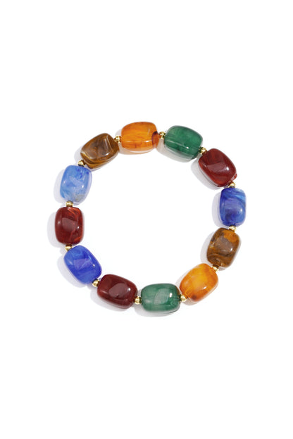 Multicolor acrylic chunky bead bracelet with gold spacers on white background featuring blue, red, green, amber, and brown beads
