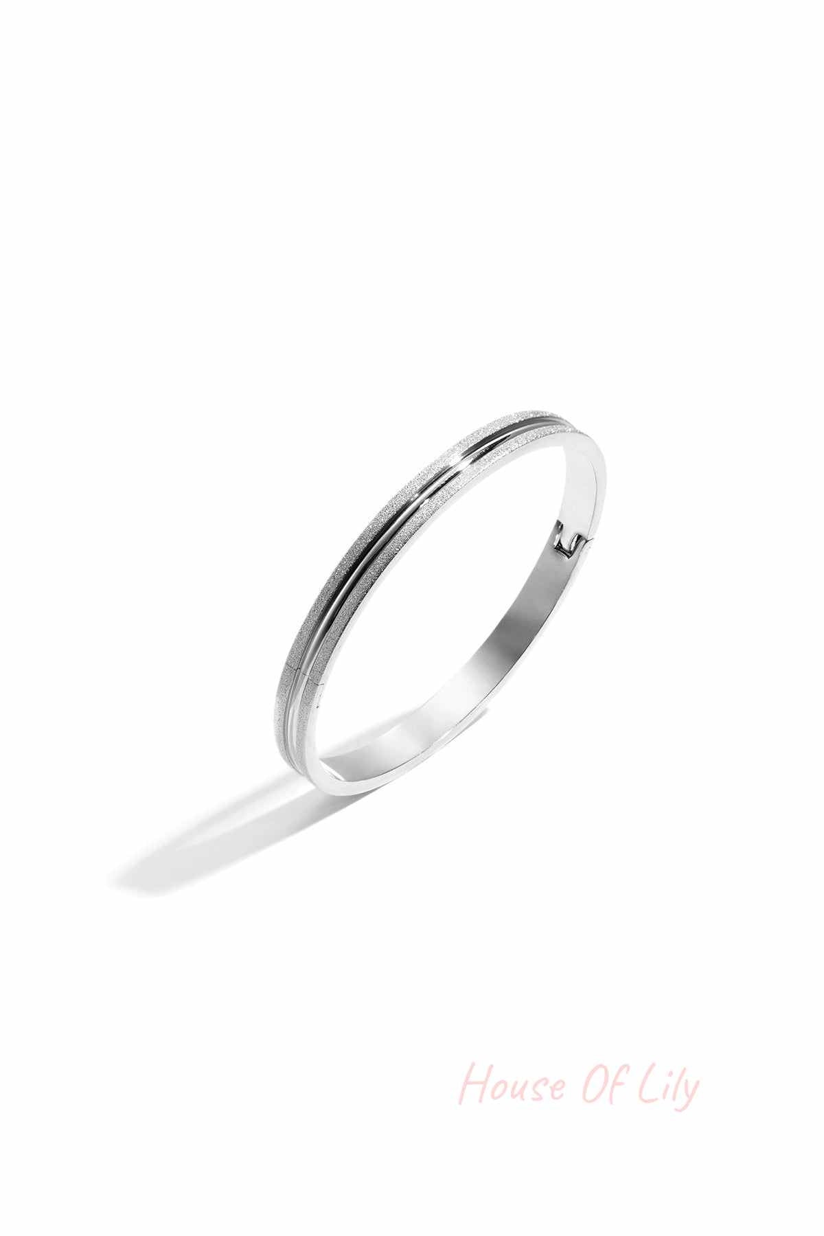 Silver-tone textured bangle bracelet with dual surface finish isolated on white background