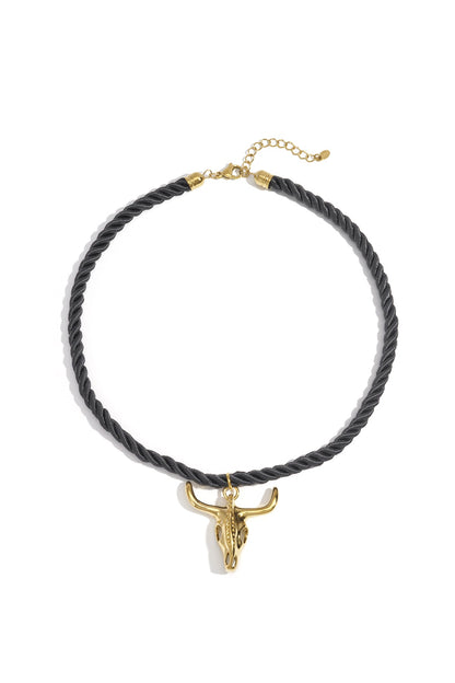 Black twisted rope necklace with gold bull skull pendant on white background