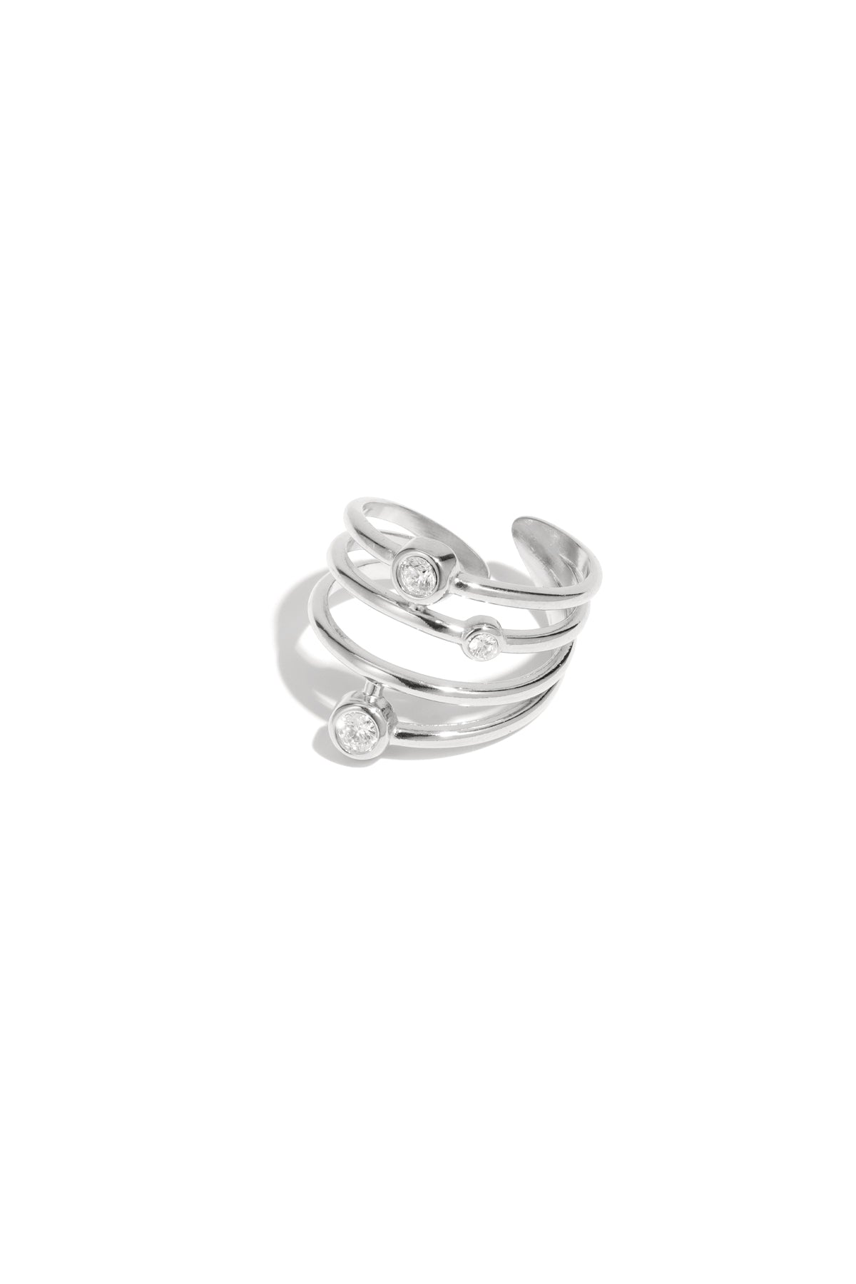 Silver tone multi-band adjustable statement ring featuring three bezel set rhinestones on white background