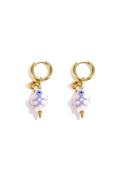 Pair of gold-tone hoop earrings with soft pastel pink ceramic fish charms featuring blue and green accents on white background