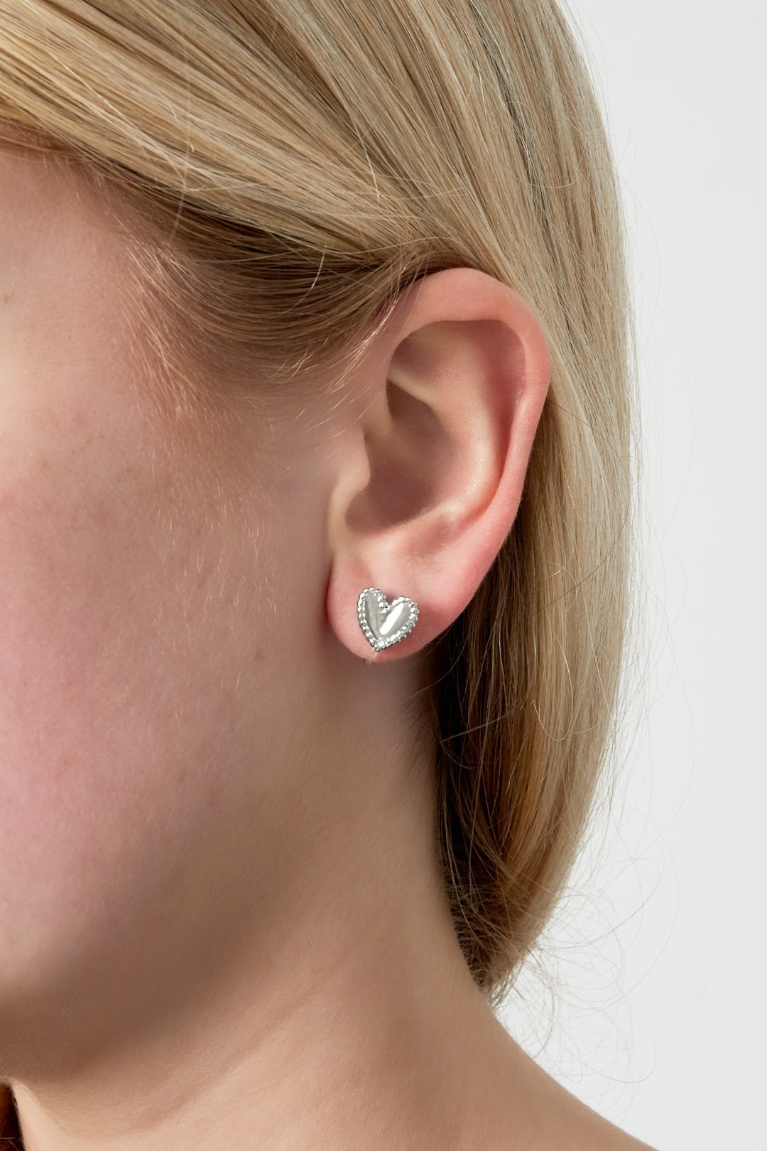 Close-up of a woman wearing silver-tone heart-shaped clip-on earring, showcasing the design and fit on the ear