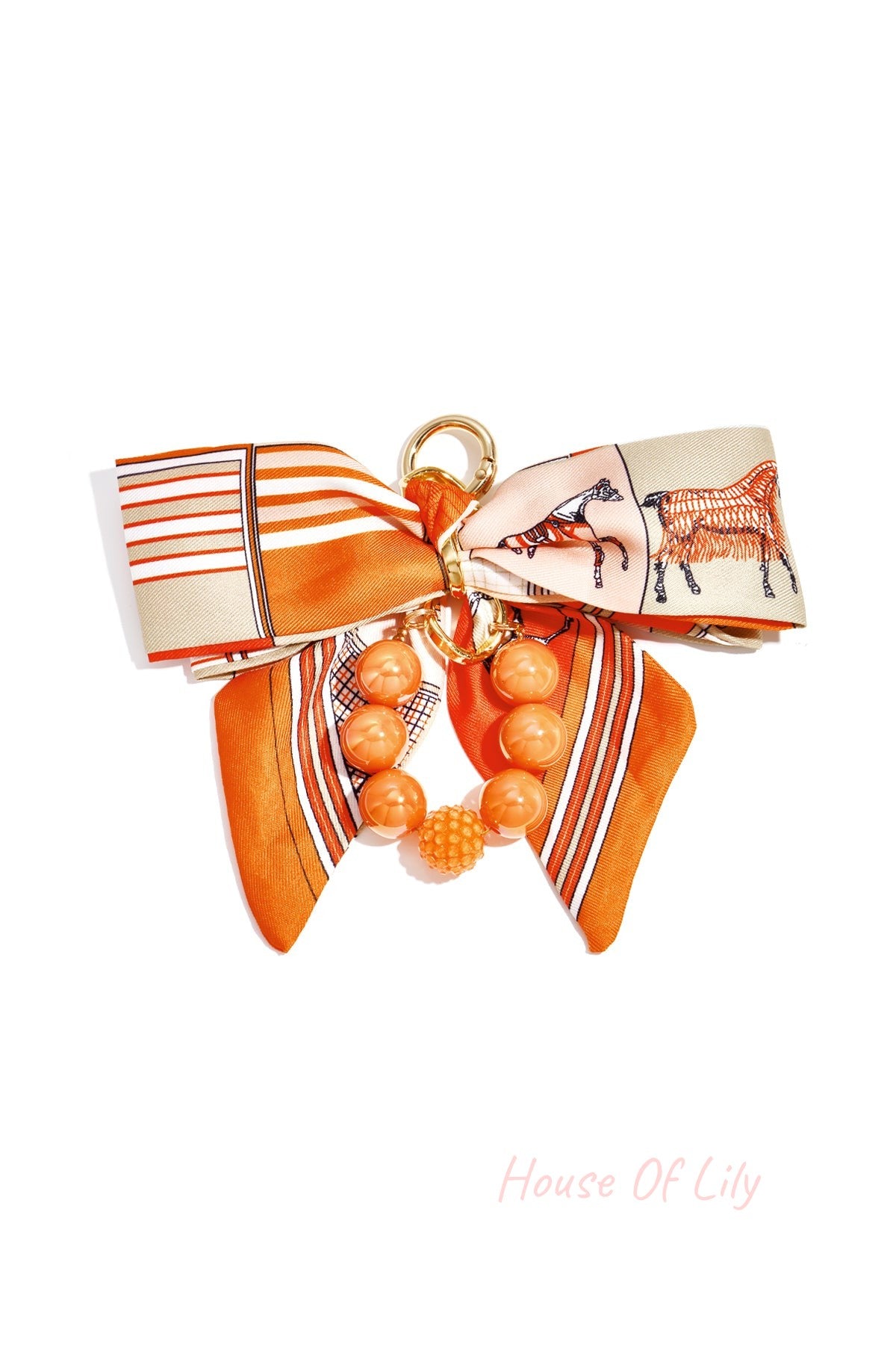 Orange patterned fabric bow with glossy matching orange and textured beads bag charm attached to gold clasp