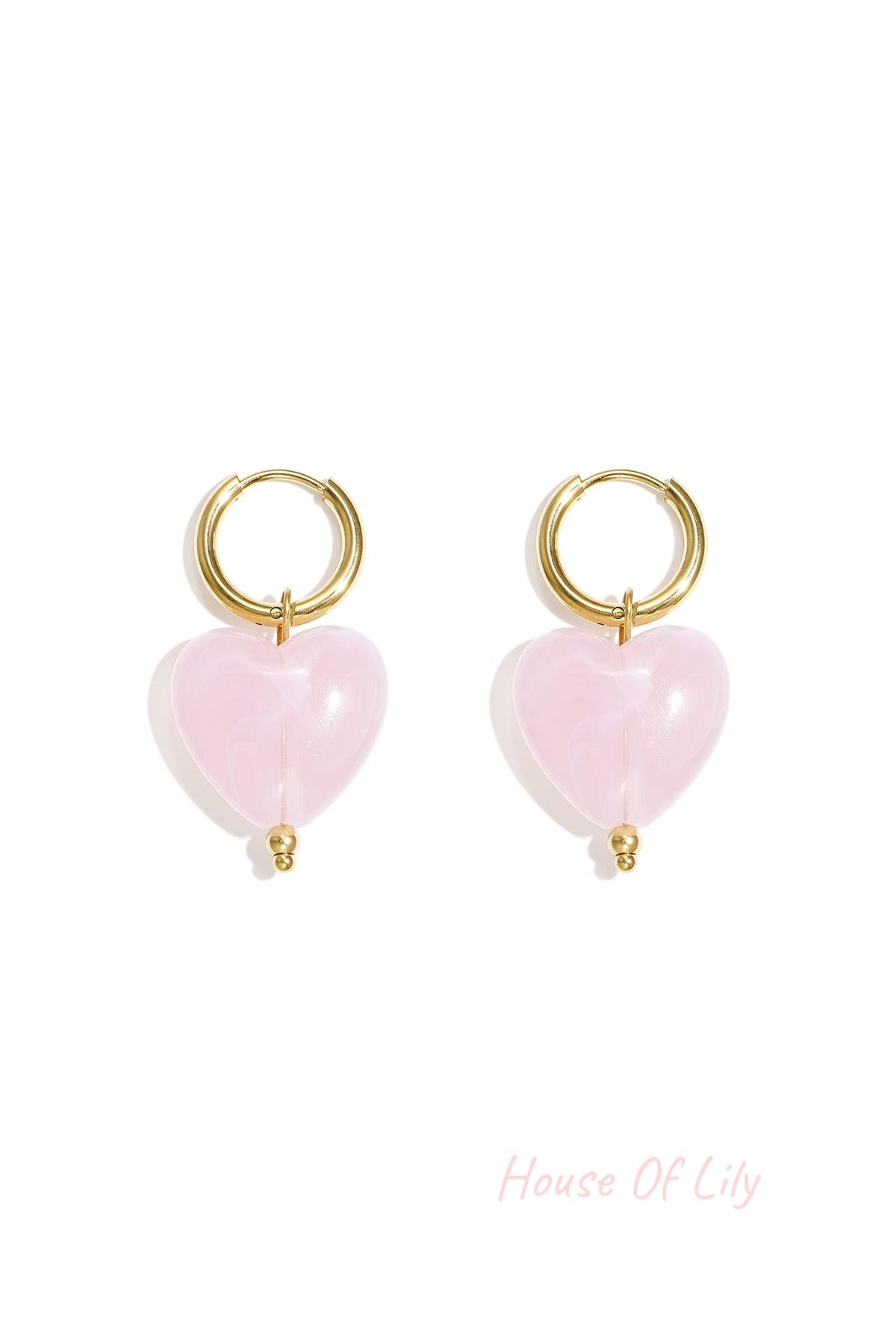 Pair of gold hoop earrings with baby blue glossy resin heart pendants on white background