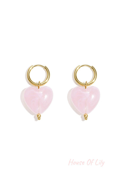 Pair of gold hoop earrings with baby blue glossy resin heart pendants on white background