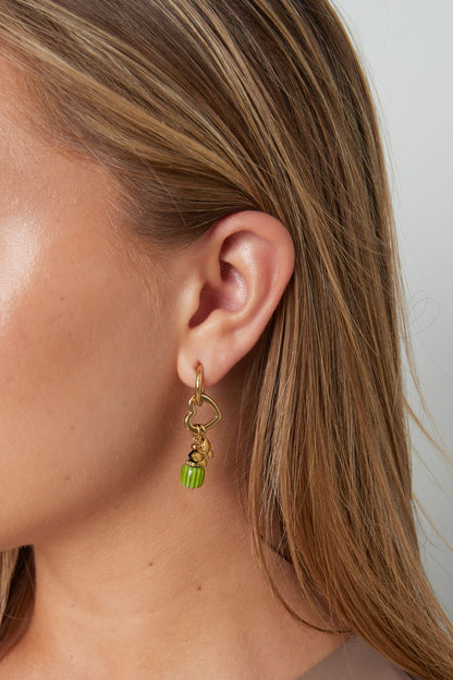 Close-up of a woman wearing gold-tone butterfly charm drop earring showing its design and how it hangs