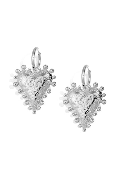 Close-up image of textured silver heart-shaped hoop earrings with rounded stud detailing on a white background