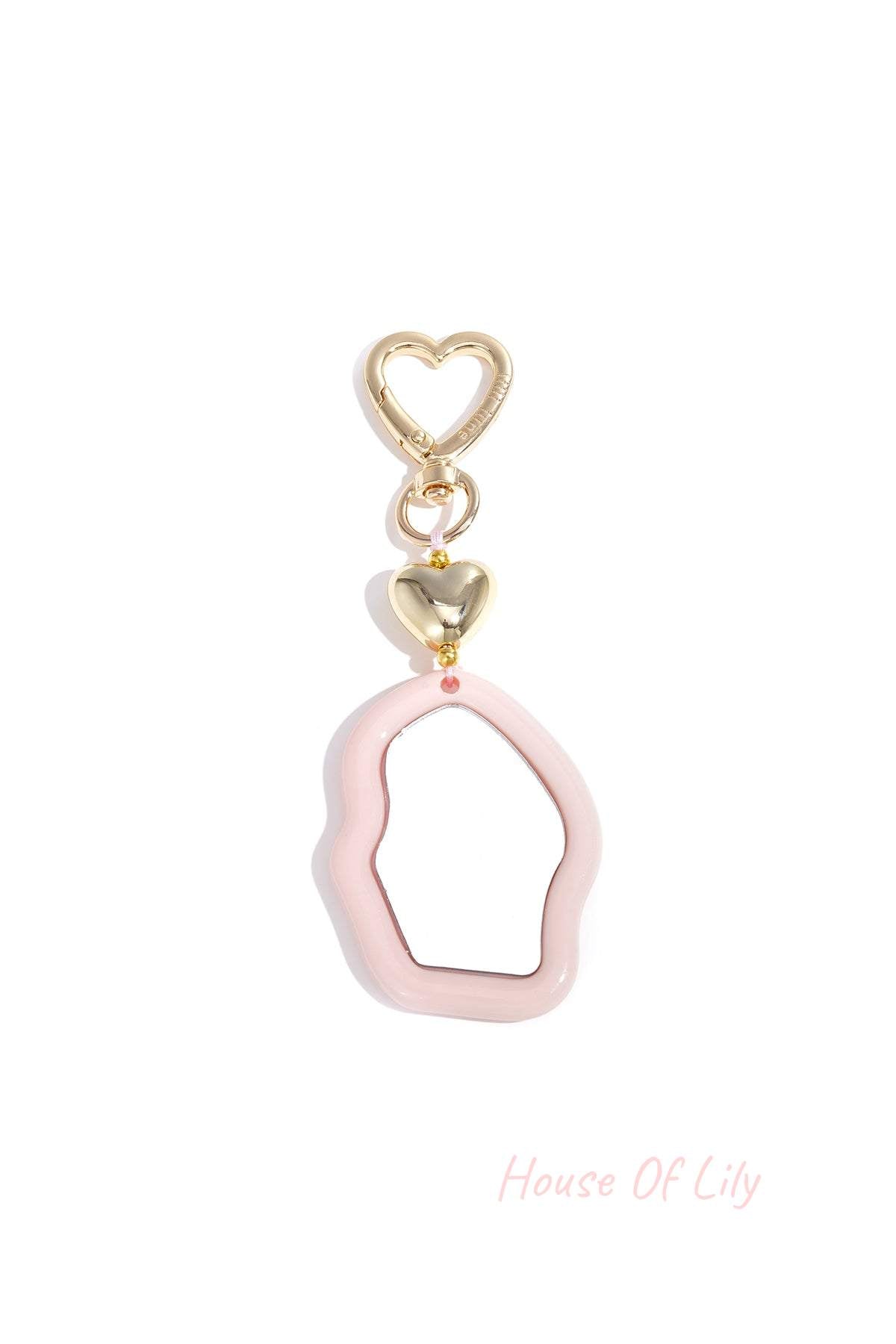 Pink acrylic irregular heart-shaped mirror charm with golden heart clasp on white background