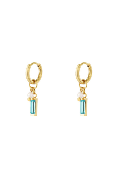 Pair of gold hoop earrings with aqua rectangular gemstone, pearl, and small bead charms on white background