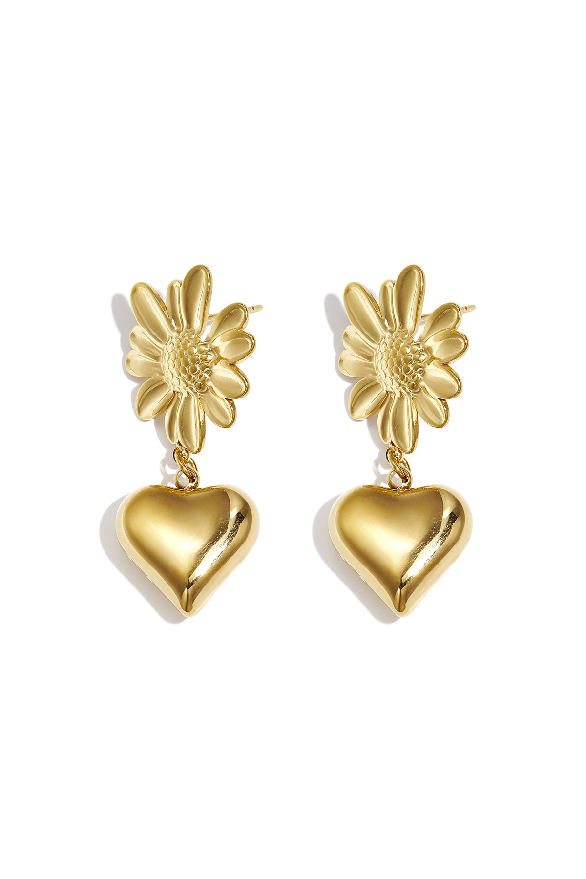Pair of gold drop earrings featuring a textured flower base and a hanging shiny heart pendant on white background