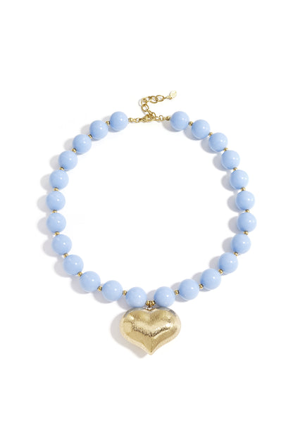 Chunky baby blue beaded necklace with a textured gold heart pendant laid flat