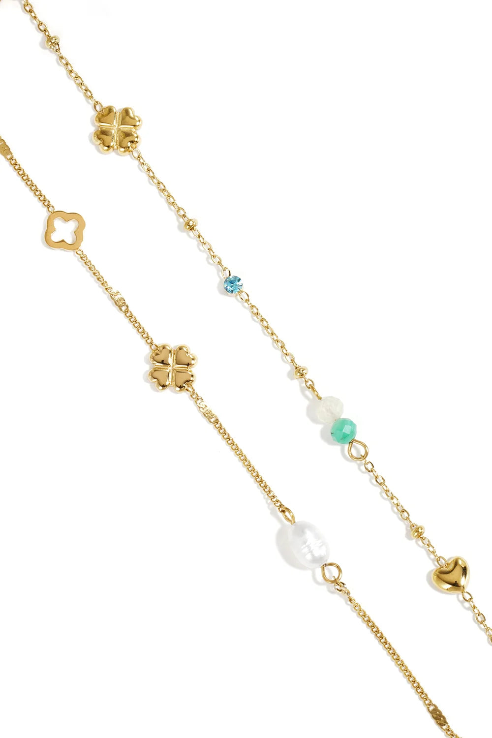 Gold charm bracelet stack with clover motifs, a pearl, small colorful gemstones, and a heart charm on a delicate chain.