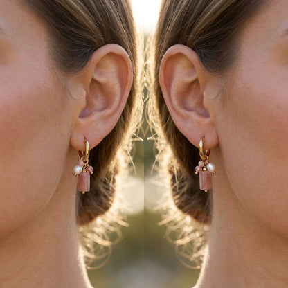 Close-up of dainty charm hoops with pearls, stones, and glass elements catching sunlight outdoors.