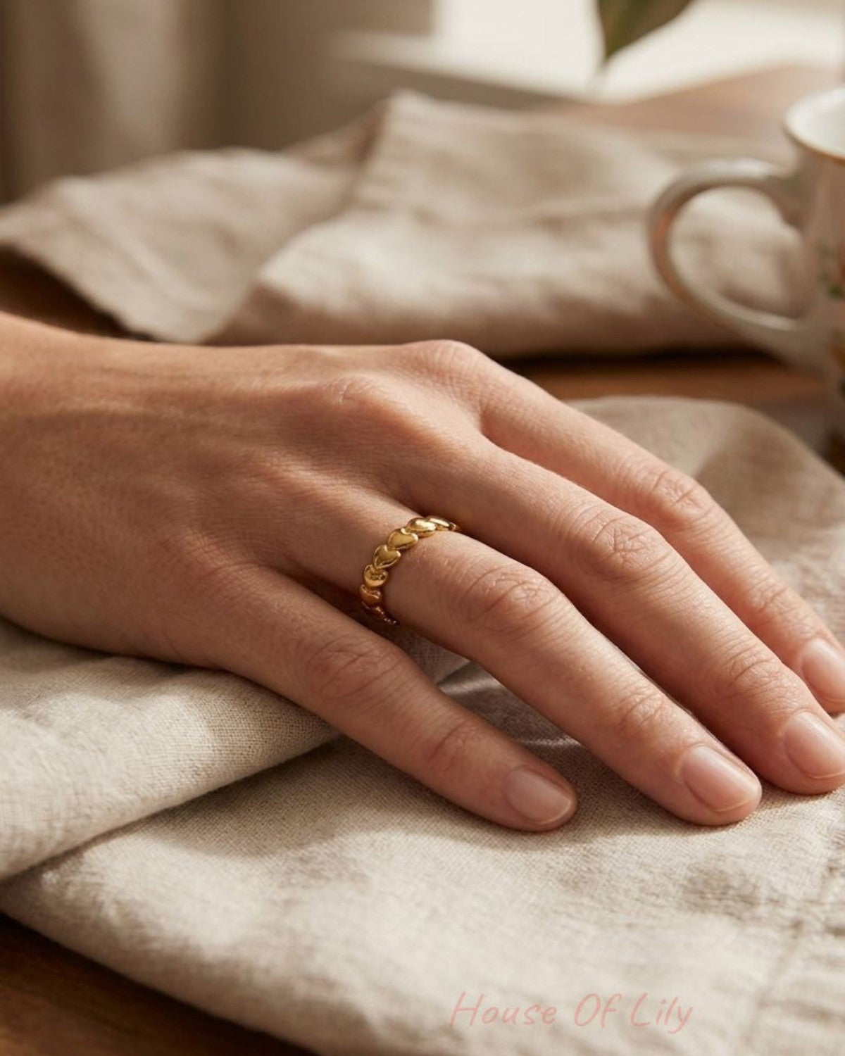 Close-up of Dainty Heart Stacking ring highlighting its delicate heart pattern and stainless steel texture on a linen surface.