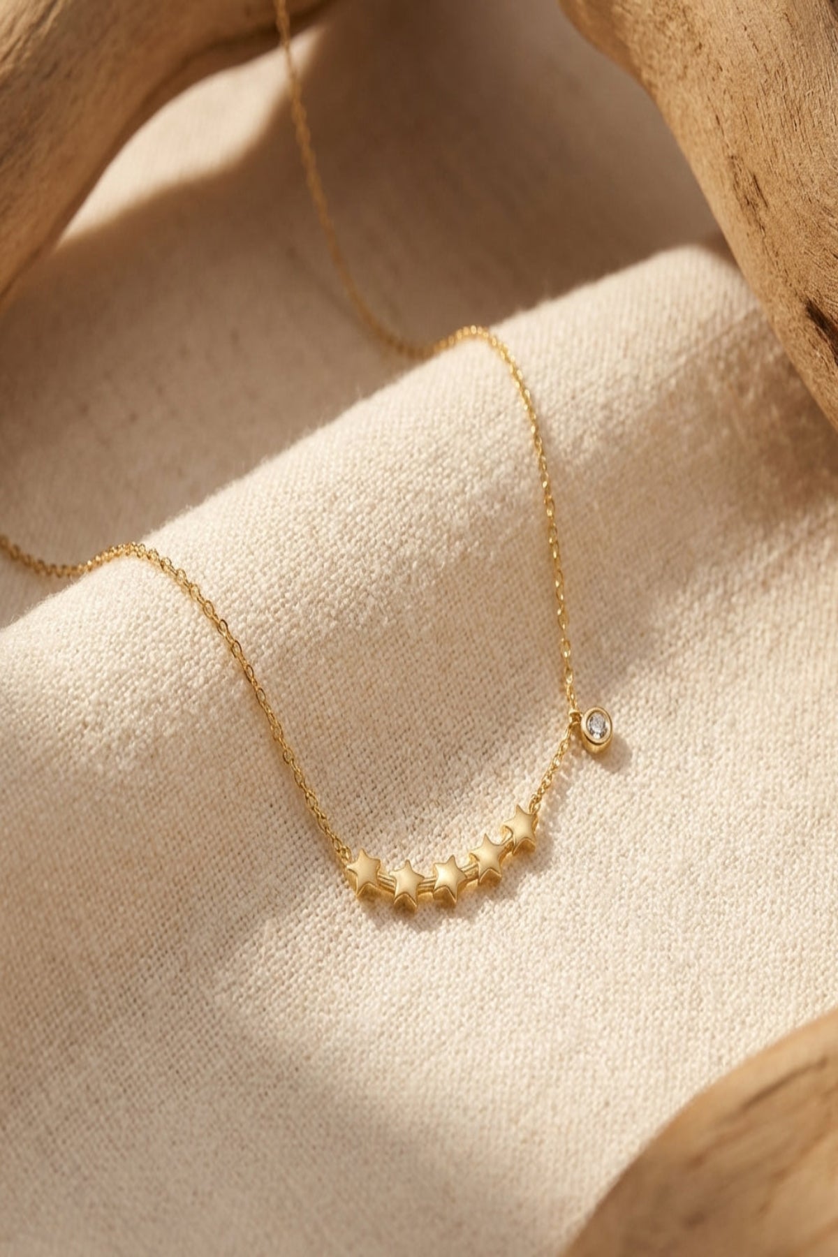 High-resolution close-up of a dainty star cluster necklace on neutral fabric, highlighting delicate rhinestone and star charms under natural lighting.