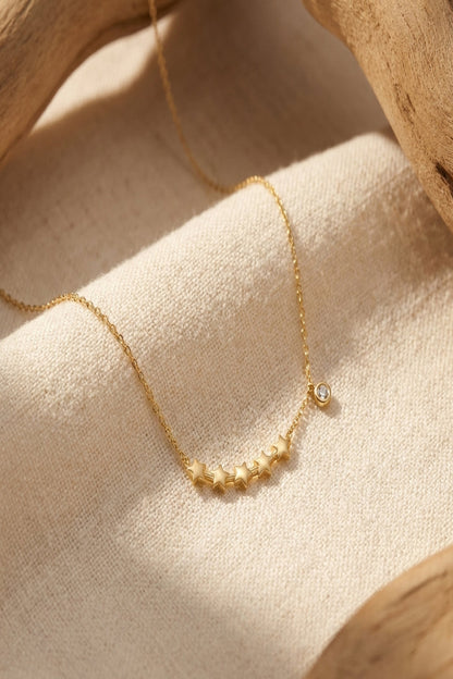High-resolution close-up of a dainty star cluster necklace on neutral fabric, highlighting delicate rhinestone and star charms under natural lighting.