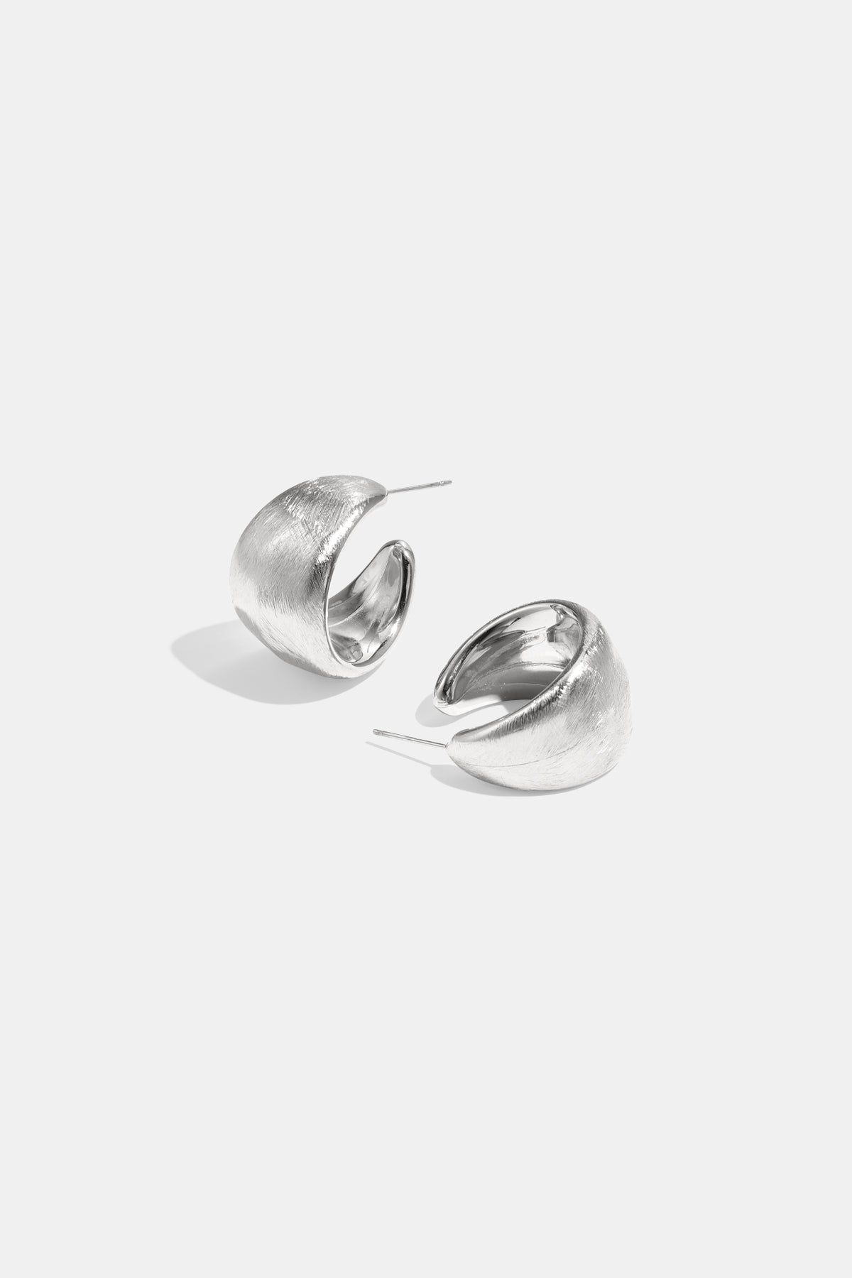 Pair of chunky textured silver hoop earrings on white background