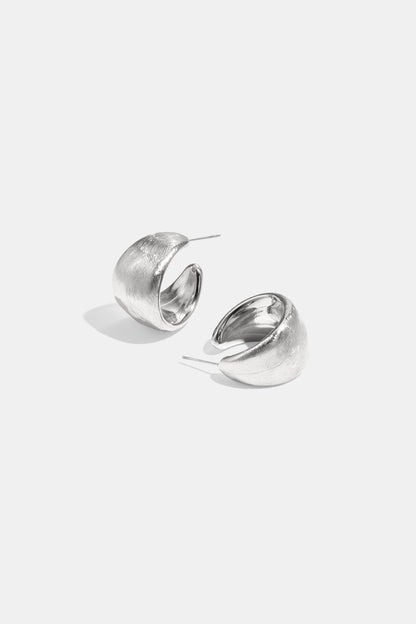 Pair of chunky textured silver hoop earrings on white background