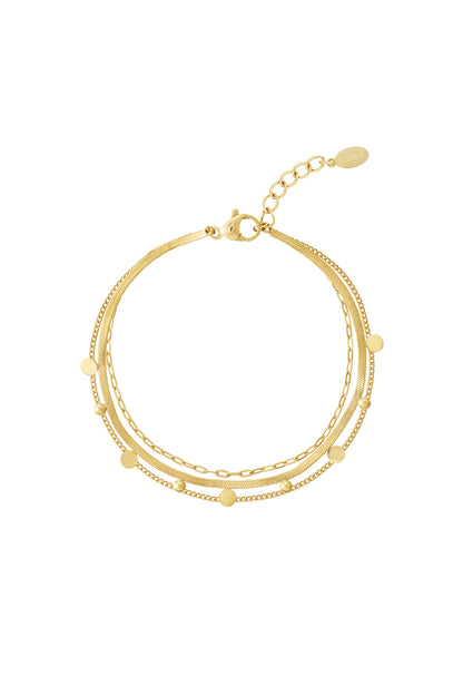 Close-up of a layered gold chain bracelet with small round dot accents and lobster clasp on white background
