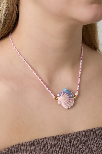 Woman wearing soft pink seashell ceramic pendant necklace on braided pink cord