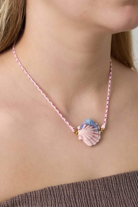 Woman wearing soft pink seashell ceramic pendant necklace on braided pink cord