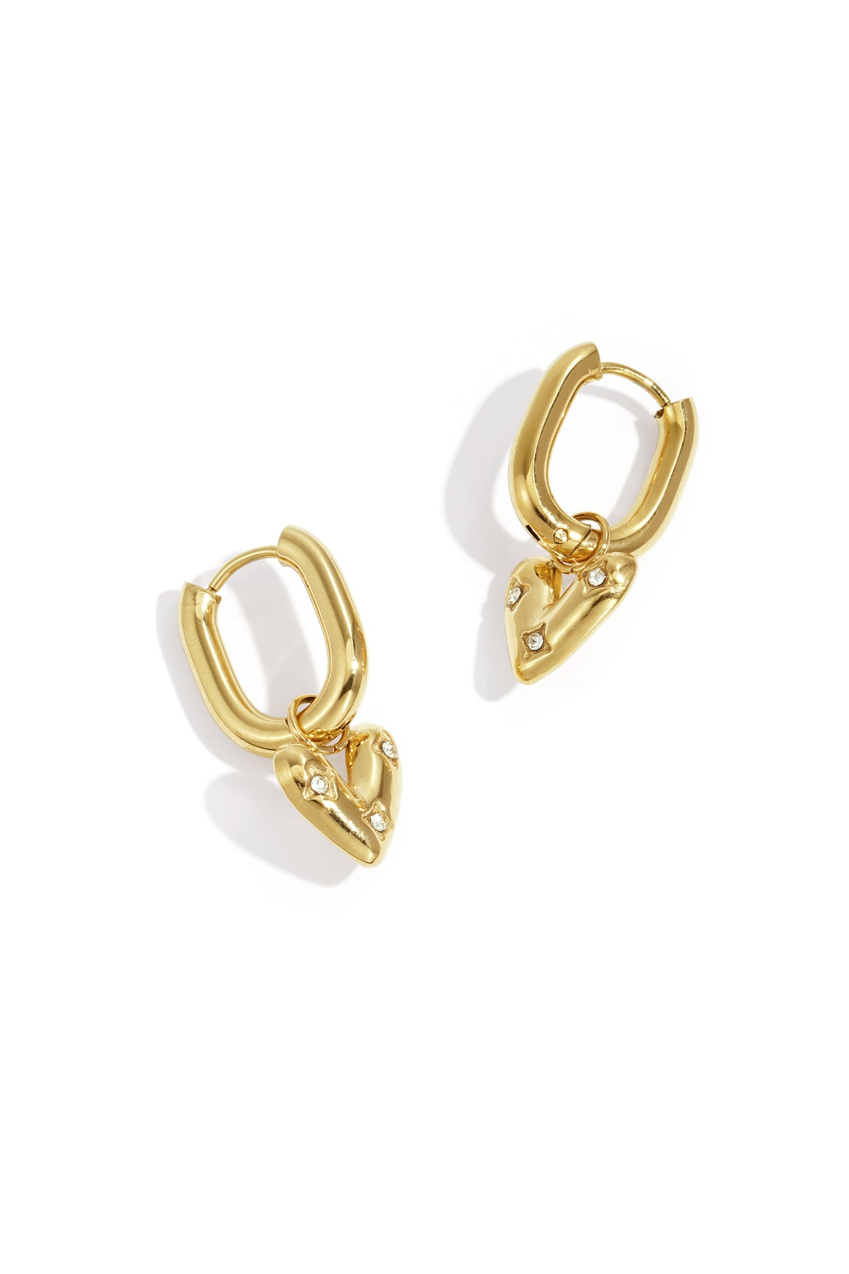 Pair of shiny gold drop earrings with small heart pendants adorned with rhinestones displayed on white background