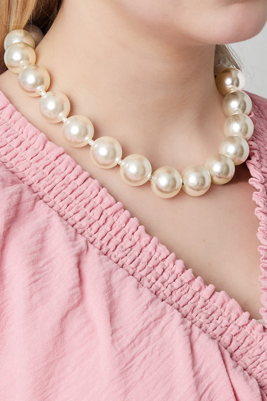 Model wearing the pearl statement necklace with large faux pearls, styled with a pink textured top showcasing the necklace's chic and youthful aesthetic