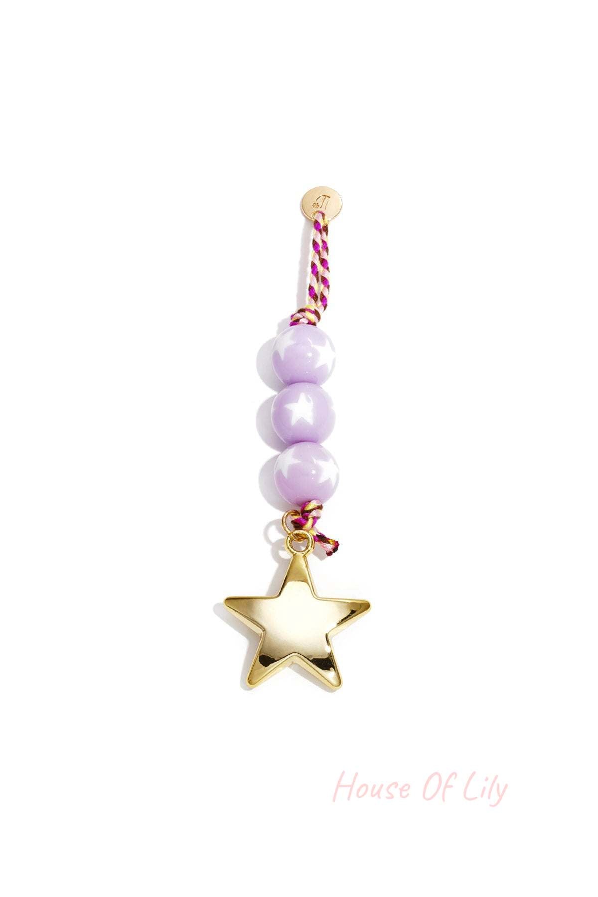 Close-up of pastel purple bead charm with shiny gold star pendant and braided cord