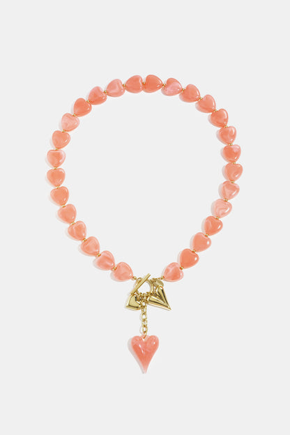 Amber brown heart bead necklace displayed on white background with gold charms and toggle clasp