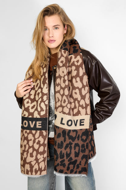 Woman wearing a large leopard print scarf draped over her shoulders paired with casual outfit