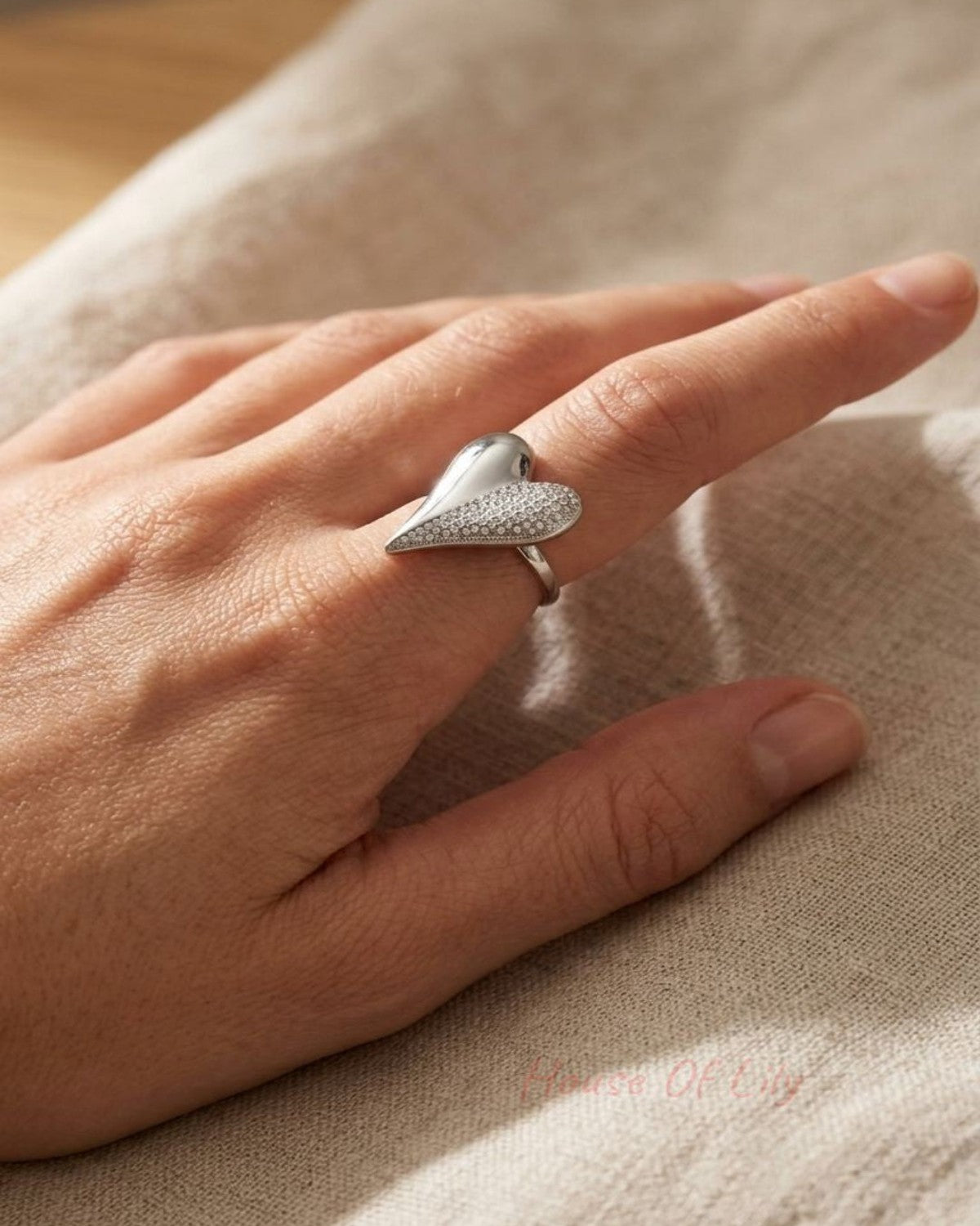 Small stainless steel heart-shaped statement ring with half-polished, half-sparkle design on a naturalistic hand.