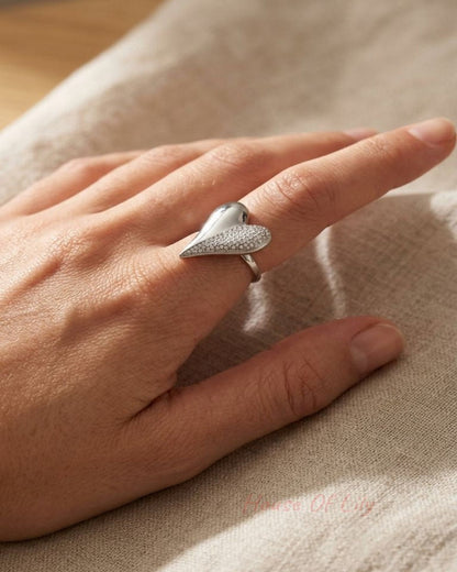 Small stainless steel heart-shaped statement ring with half-polished, half-sparkle design on a naturalistic hand.