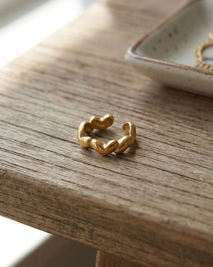 Small stainless steel 'Infinite Love Loop' ring on wooden surface with natural daylight highlighting its minimalistic open band design for everyday wear.