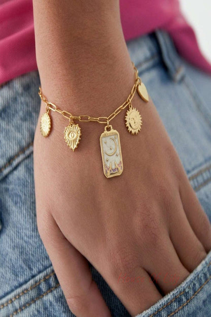 Tiny charm bracelet labeled 'magic moon' with moon charm, resting on reflective wooden surface, highlighting its delicate design.